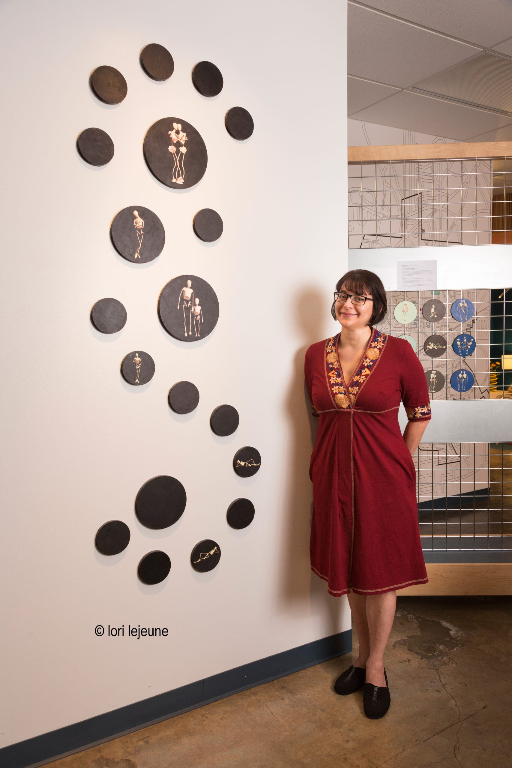 lori jejune, lady in red dress standing by art installation